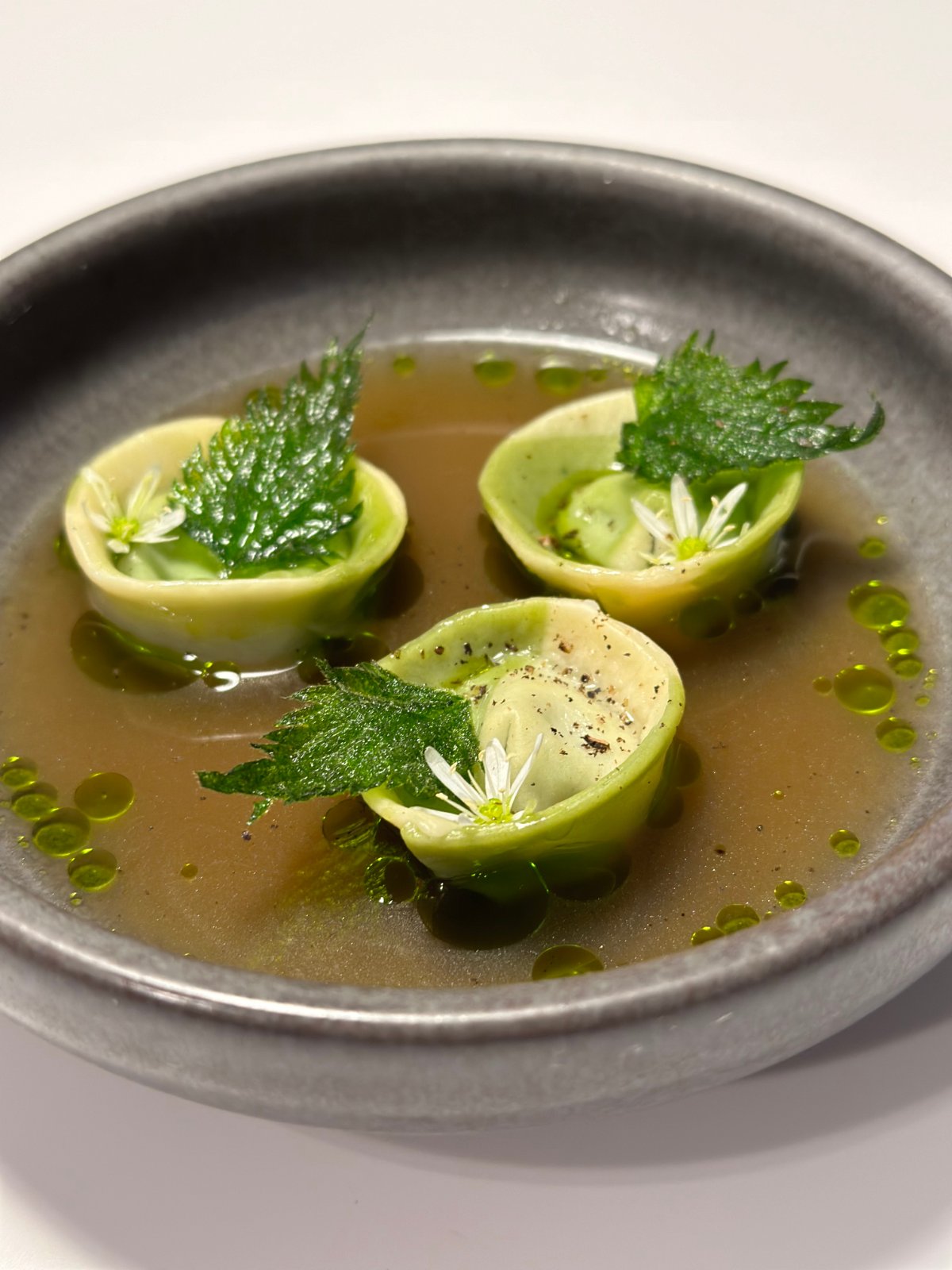 Tortelli filled with nettles pesto in a warm roasted chicken broth, finished with ramson oil